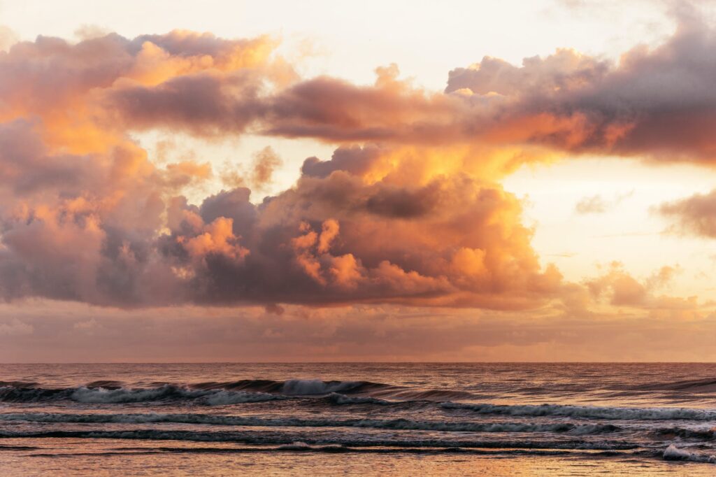 fluffy sunset clouds above waves